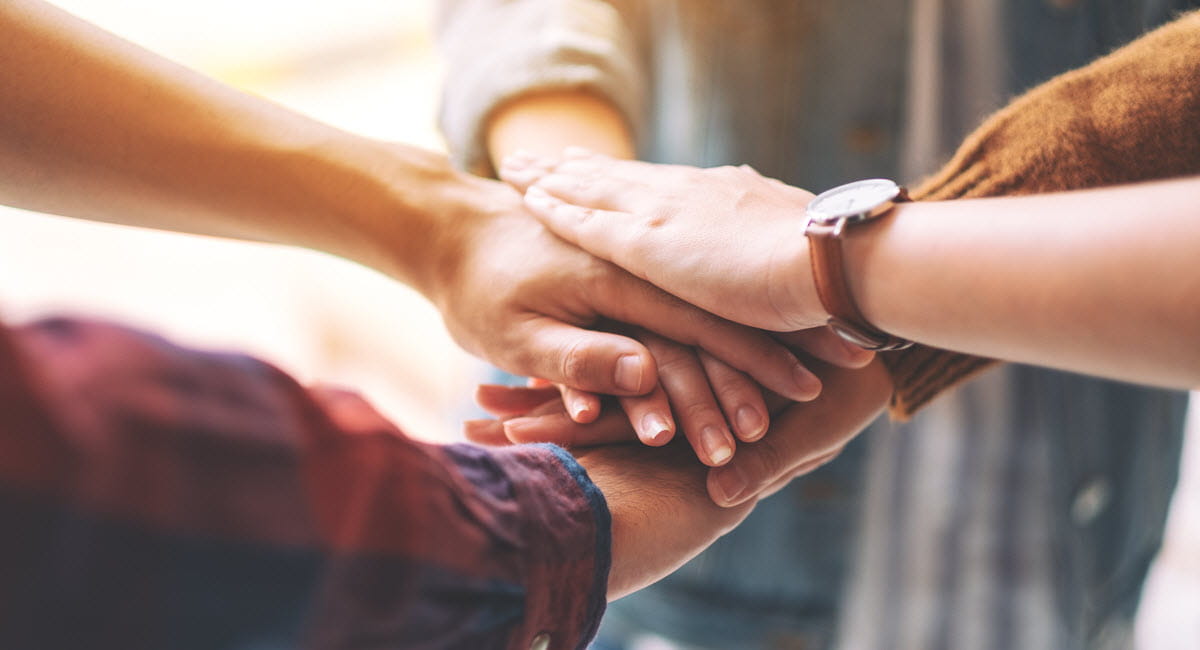 coworkers putting their hands together in the meeting 