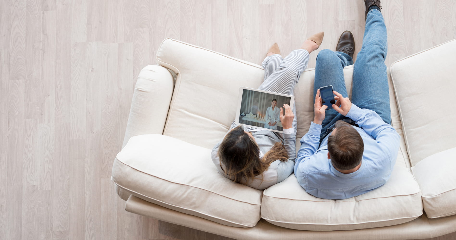Couple sitting on sofa and using digital table and smartphone